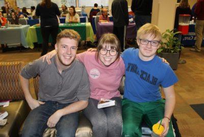 三个面带微笑的学生坐在沙发上，背景是咨询台