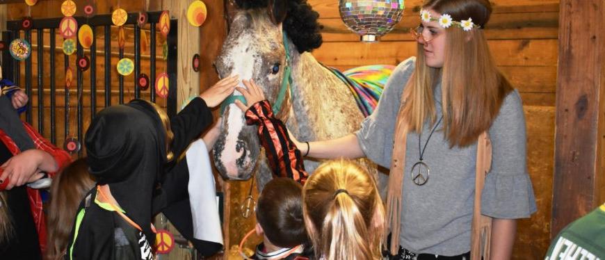 学生和马穿着迪斯科服装，孩子们穿着戏服抚摸着马