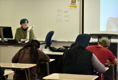 助理教授讲课时，学生们坐在课桌前