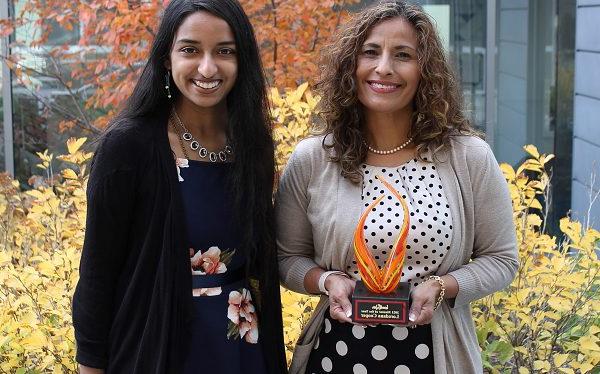 Loredana库珀 holding award with Saheli Sheth standing outdoors on fall day